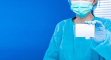 Surgeon doctor hold empty blank paper document. Medical person wear blue uniform glove mask in hospital to show responsibility ethic moral to social as professional healthcare, copy space photo