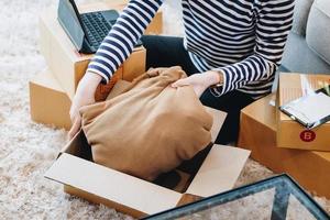 Online merchandising business idea, a beautiful girl is packing pillows in a shipping box to prepare to send items to customers according to orders received from customers. photo