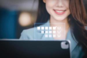 una empresaria o mujer de negocios que muestra una cara sonriente mientras opera una tableta de computadora que trabaja en una mesa de madera. foto