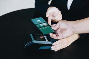 concepto de tecnología de seguridad de pago y tarifas de servicio, los empleados tienen máquinas de tarjetas electrónicas para que los clientes usen el teléfono inteligente móvil para pagar a través de la tecnología paywave. foto