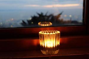 light candle near the window with scenery view. For use as wallpaper or background with copy space. Winter, new year, Christmas, winter, hugge, holiday concept. photo