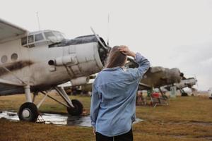 hermosa mujer joven de pie cerca del avión. viajes y tecnología. vista trasera foto