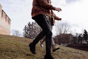 foto recortada de una joven pareja amorosa corriendo por la calle al aire libre tomándose de la mano.