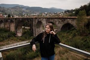 Woman tourist enjoys traveling to historical places in Ukraine, viaduct in the mountain resort village of Vorokhta photo
