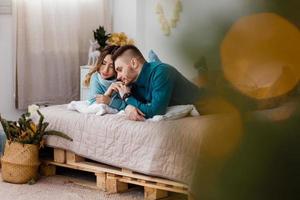 Happy couple in christmas decoration at home. New year eve, decorated fir tree. Winter holiday and love concept.Young happy couple embracing and relaxing on comfortable couch. photo