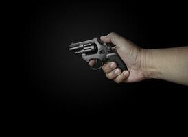 male hand holding a black revolver on a black background Criminals with handguns at close range Weapons for attack or defense