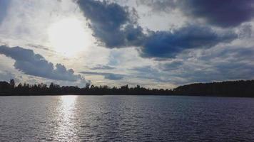 puesta de sol atmosférica detrás de los árboles y reflejo en el agua. foto