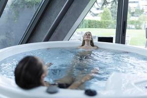 Shot of two young women relaxing in a jacuzzi. friends having a day in spa photo