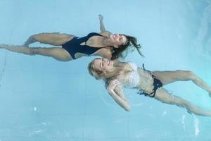 mujeres en el agua de la piscina. hermosas mujeres felices con cuerpo en forma sexy relajante, flotando en la piscina en el hotel spa. vacaciones de verano vacaciones. estilo de vida saludable. bienestar, belleza, recreación foto