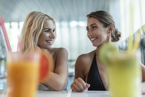 Attractive young female friends having fun near swimming pool. photo