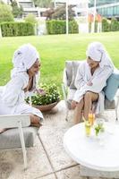 Happy young beautiful women enjoying fun time after spa procedures together in luxury hotel, wearing towels on heads and bathrobes. photo