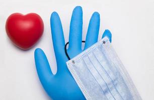 A heart-shaped antistress pulse sponge next to a medical glove and a mask