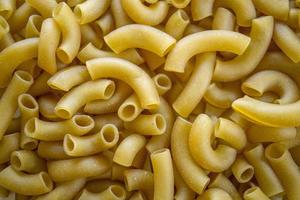 Uncooked and dry macaroni textured background, food macro close-up background. photo