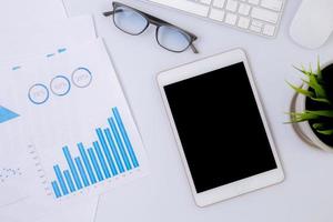 Work from home, business with tablet and graph of report financial of profit or earning on desk, statistics of marketing and investment, document of diagram and chart for planning strategy on table. photo