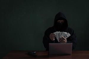 Black Hat Hacker Counting Banknote While Hacking Information From Bank. Cyber Security Concept photo