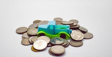 A blue-green pickup truck surrounded by piles of coins on a white background. photo