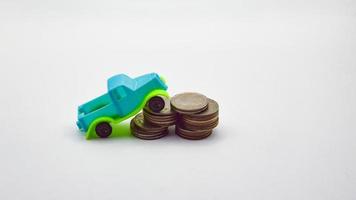 Blue-green pickup truck climbs a pile of coins on a white background. photo