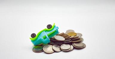 Blue-green pickup truck overturned.  on a pile of coins on a white background photo