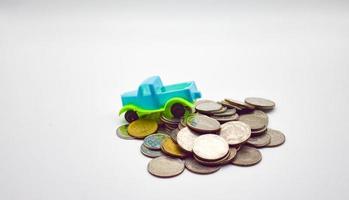 A blue-green pickup truck climbs on a pile of coins on a white background. photo