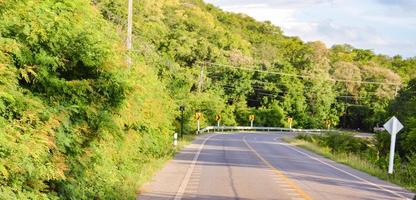 Scenery. The paved road with a slope on the hill.  surrounded by green forest  sunny outdoors  Copy space, concept, travel with environmental conservation. photo