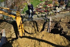 A combination of heavy excavator equipment and human masonry work during cesspool digging photo