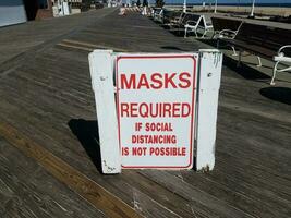 masks required if social distancing is not possible sign on boardwalk photo
