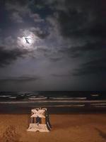 luna llena en la playa con algunas tumbonas foto