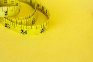 Yellow measuring tape with customizable space for text or ideas. Copy space and weight loss concept photo