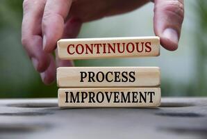 Continuous process improvement text on wooden blocks with blurred nature background. Process improvement and business concept photo