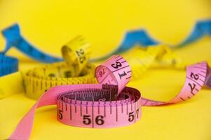 Red, yellow and blue measuring tapes on yellow cover background. Copy space and weight loss concept photo