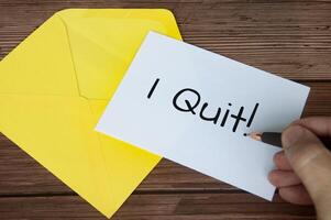 Hand writing I quit text on white notepad with yellow envelope background. Employment concept photo