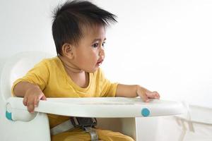 Cute white girl sitting chair eating breakfast in indoor home feeding delicious meals that are highly nutritious the baby has a cheerful face funny smiling and happy in a healthy family lifestyle. photo