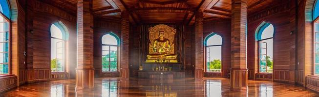 Teak hall and golden Buddha statues inside the temple chedi illuminated by the windows. Make you feel amazed by the beauty of the pagoda. photo