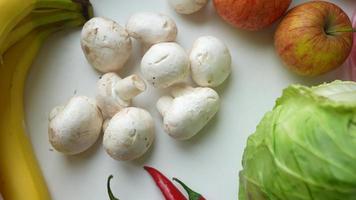 Fresh produce on white countertop including mushrooms bananas apples and cabbage video