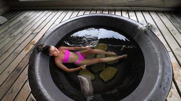 Woman in pink bikini relaxes in an outdoor hot tub video