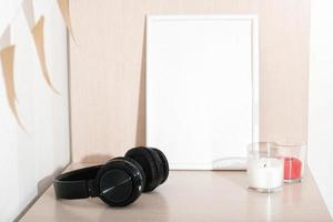 white empty frame next to soy candles and headphones. teenagers room, cozy style, scandinavian design. copy space for text. photo