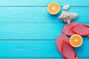 Summer fun time and flip flops. Sea shell. Slippers and orange fruit on blue wooden background. Mock up and picturesque. Top view. Copy space photo