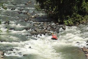 foto de actividades de rafting realizadas por un grupo de personas en un río rocoso con fuertes corrientes