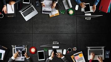 Top view of business Group of Multiethnic Busy People meeting with other in modern office with laptop computer, smartphone, tablet, coffee and document on table. photo