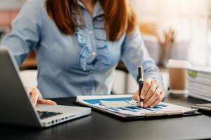 Bussinesswoman analyzing sales data and economic growth and pointing at business report document with graph chart financial chart marketing, banking and payments at modern office photo