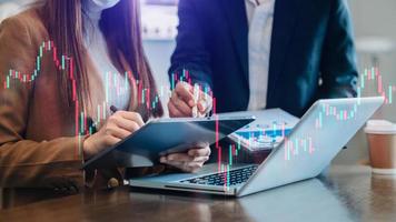 Two professional traides on technical price graph and indicator, red and green candlestick chart and stock trading computer at office photo