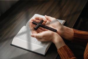 Woman sitting and studying the scriptures.The  wooden cross in the hands. Christian education concepts The Holy Scriptures open and pray to God. photo