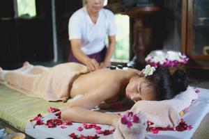 Massage and spa relaxing treatment of office syndrome using hot stone traditional thai massage style. Asian female masseuse doing massage treat back pain, arm pain, stress for woman tired from work. photo