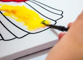 children hand painting yellow color on canvas photo