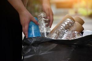 Houseowner is separiting bottles, paper, egg cartons and other stuffs in the black plastic bag in front of the house, concept for reducing global warming, saving our world, soft and selective focus. photo