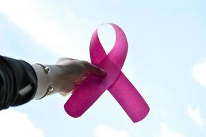 cinta de papel rosa en manos de una adolescente para mostrar y llamar a todas las personas del mundo a apoyar y asistir a la campaña de cáncer de mama de la mujer, enfoque suave y selectivo. foto