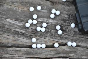 Closeup of white plastic bullets of airsoft gun or bb gun on wooden floor, soft and selective focus on white bullets. photo