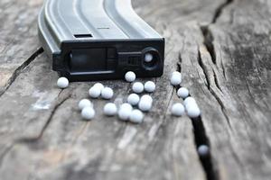 Closeup of white plastic bullets of airsoft gun or bb gun on wooden floor, soft and selective focus on white bullets. photo