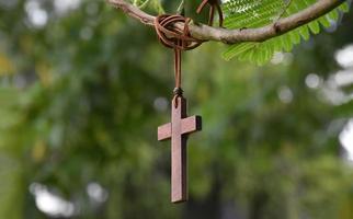 cruz de madera colgada en la rama de un árbol, enfoque suave y selectivo, fondo de árbol natural, concepto de esperanza, amor, perdón y creencia en Jesús en todo el mundo. foto