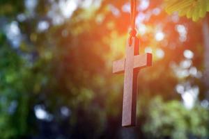 Wooden cross hanging on tree branch, soft and selective focus, natural bokeh tree background, concept for hope, love, forgiveness and belief in Jesus around the world. photo